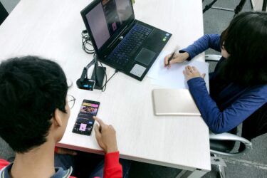 UX testing with two people, one taking notes and one reading a screen and scrolling.